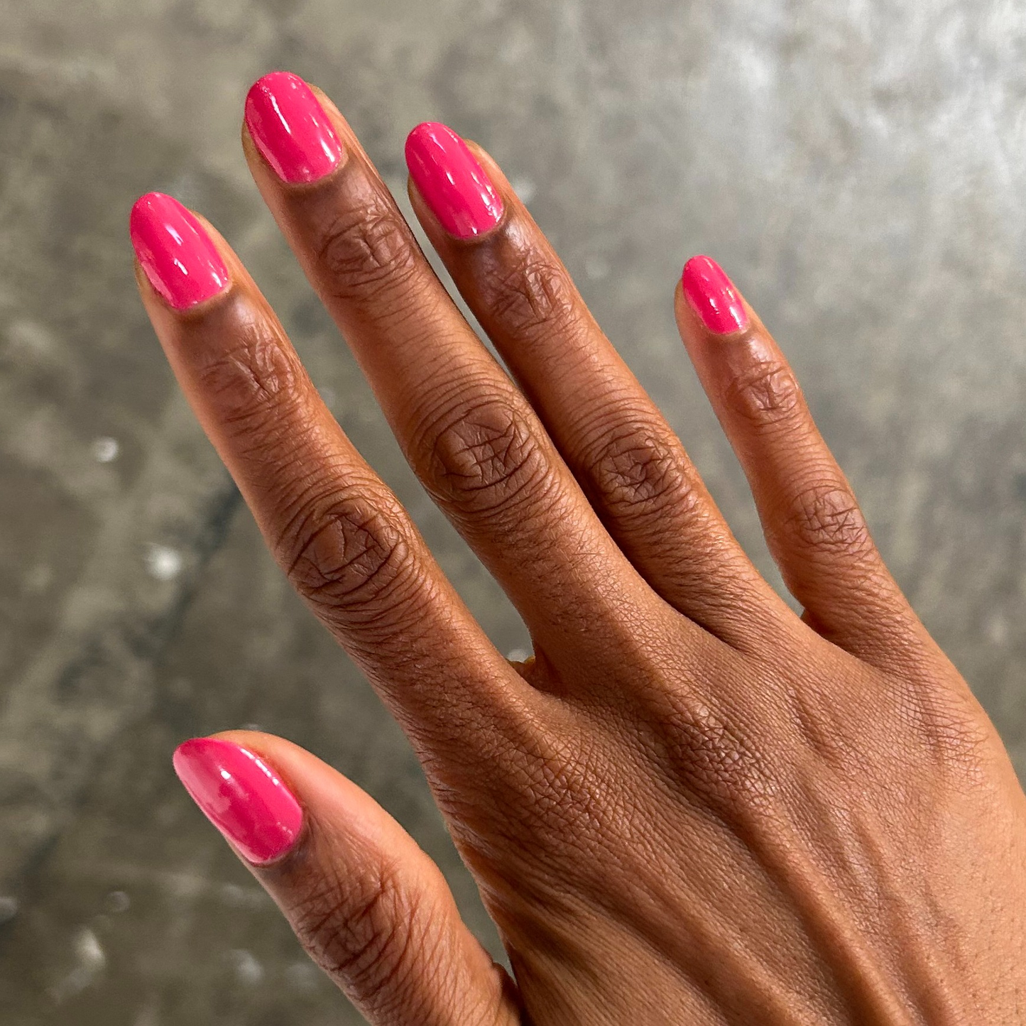 Hand with nails painted in bright hot pink Love All polish for a glossy and vibrant at-home manicure look