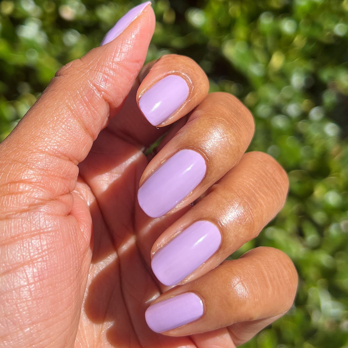 Hand with nails coated in You're Invited lilac gel polish by Olive and June for a smooth, durable manicure finish