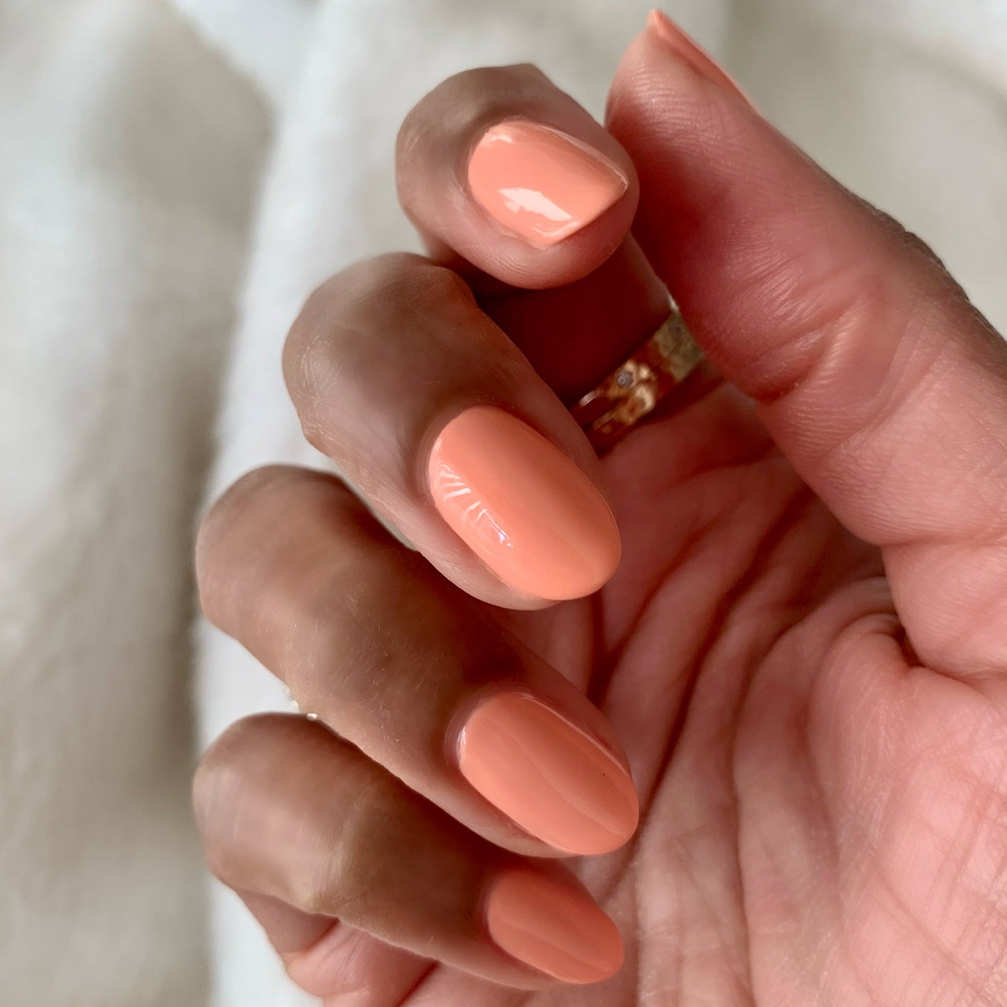 Hand with nails painted in soft coral shade Wild & Free for a smooth, long-lasting at-home manicure look