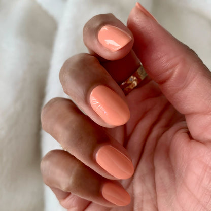 Hand with nails painted in soft coral shade Wild & Free for a smooth, long-lasting at-home manicure look