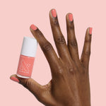 Hand with smooth nails painted in carrot orange gel polish holding Carrot Juice nail polish bottle by Olive and June