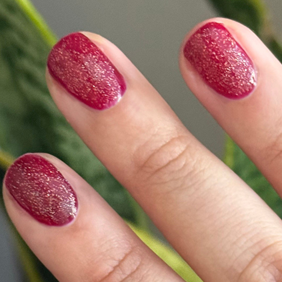 The Celestial Effect Top Coat enhancing a deep red manicure with fine shimmering micro-shimmer for a sparkling finish