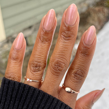 Hand with almond-shaped nails painted in glossy Sandy Scallop gel polish showing a soft golden neutral manicure