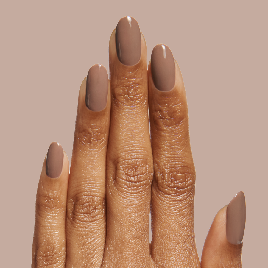 Hand showing a neutral minky brown manicure with Fawn - Gel polish on natural nails against a beige background