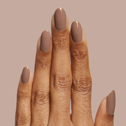 Hand showing a neutral minky brown manicure with Fawn - Gel polish on natural nails against a beige background