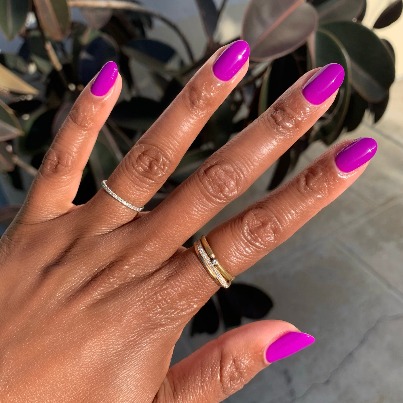 Hand with nails painted bright neon purple Grape Soda polish showing smooth glossy at-home mani in natural light