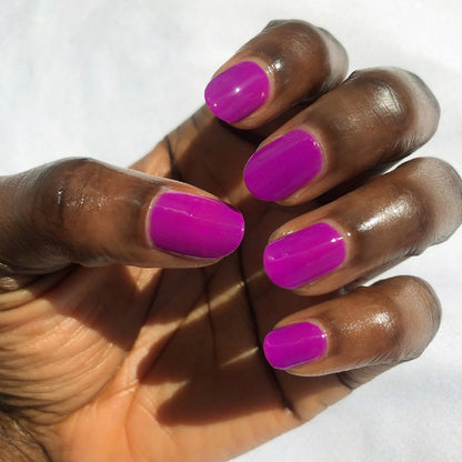Close-up of hand with nails painted bright purple Grape Soda polish showing glossy manicure in natural light