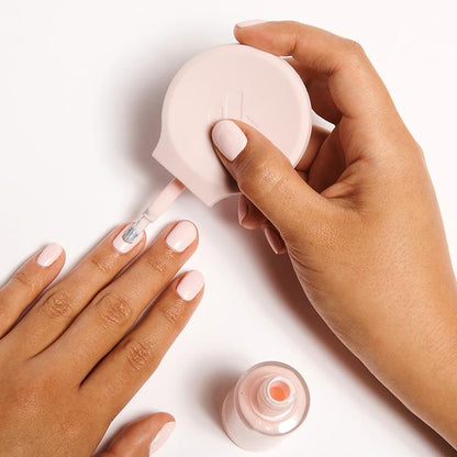 Hand using The Poppy universal polish handle to apply light pink nail polish for easier at-home mani control