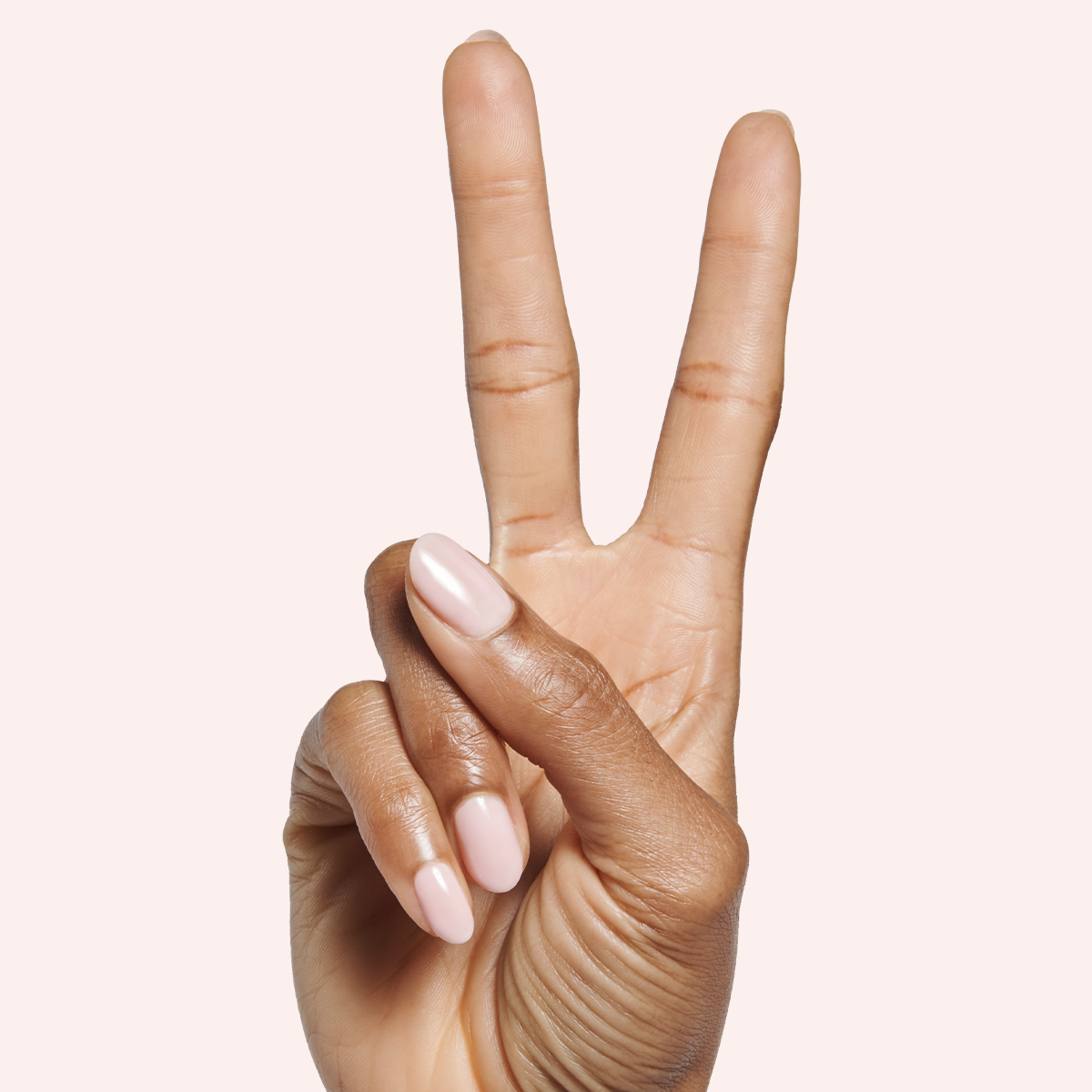 Hand with Dream Job - Gel neutral sheer pink gel polish manicure shown on medium brown skin tone against pale background