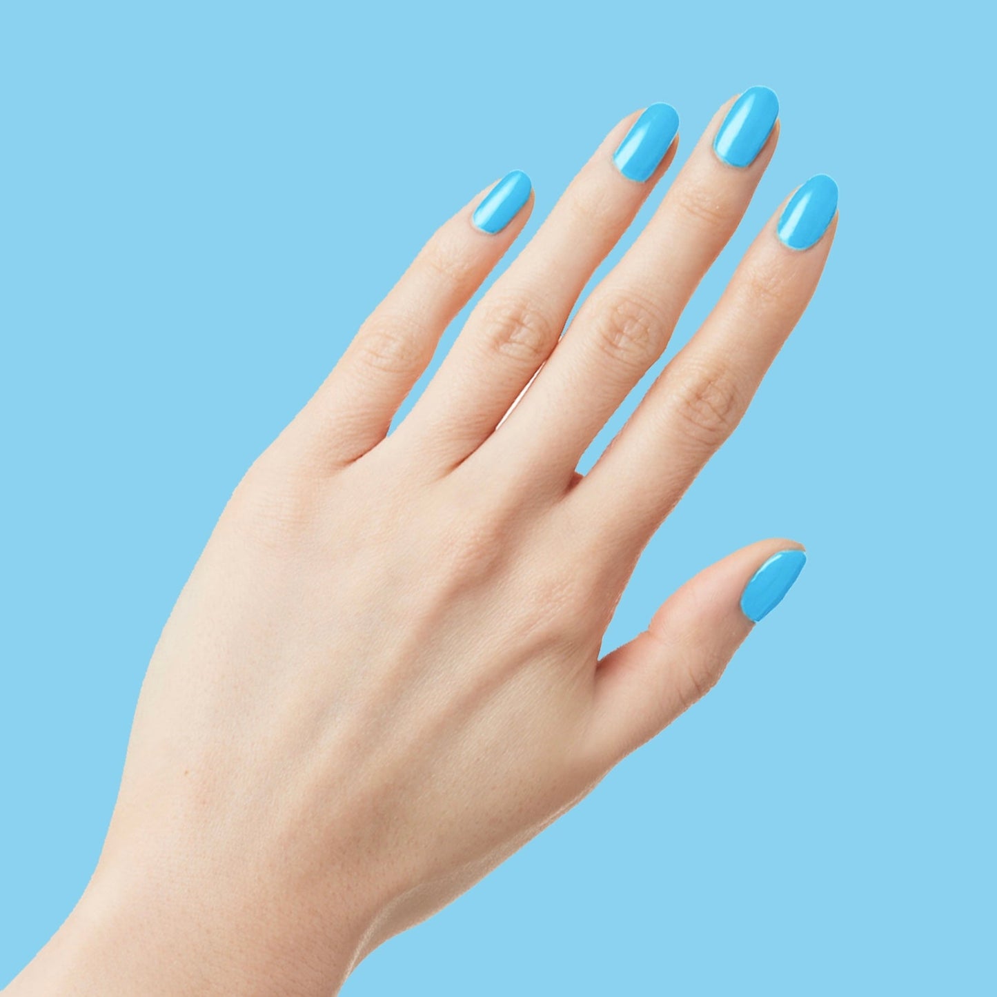 Hand showing neatly manicured nails painted with glossy Megababe Blue gel polish against blue backdrop