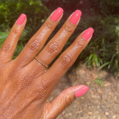 Hand showing nails polished in Stinson Sunset gel polish by Olive and June for a bright manicure outdoors