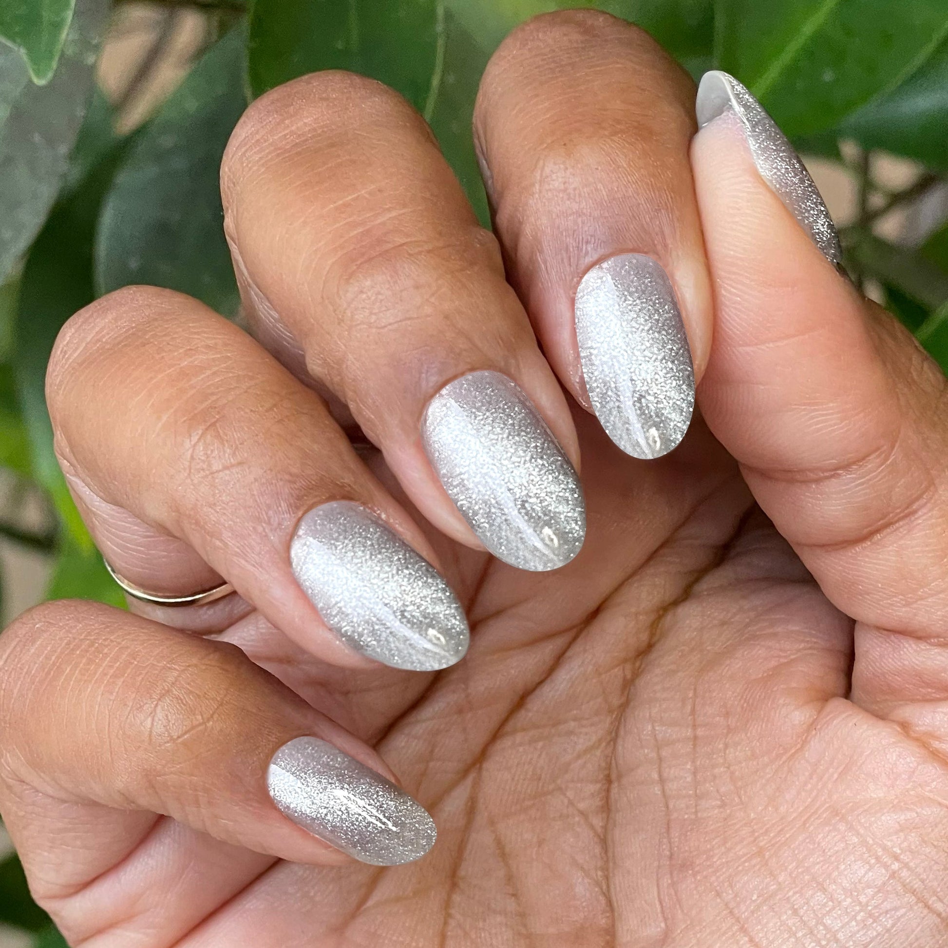 Hand with nails painted in Platinum Velvet - Gel sheer silver shimmer magnetic polish showing soft sparkle effect