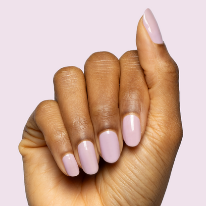 Hand with oval nails painted in Dreamy sheer milky pastel lavender gel polish for a delicate at home manicure look