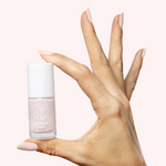 Hand holding Puffball quick dry gel polish bottle with nails painted in sheer milky pink manicure