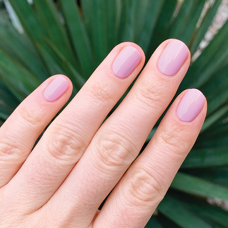 Hand with short nails coated in glossy Cockatoo gel polish by Olive and June for a smooth at-home manicure