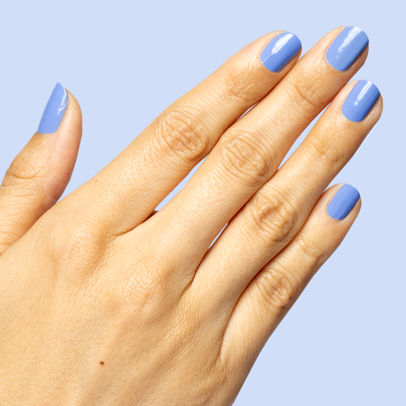 Hand with glossy nails painted in dusty ultramarine blue Rally Ready polish for a sporty at-home manicure look
