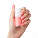 Hand with nails polished in Stinson Sunset gel polish by Olive and June holding matching nail polish bottle