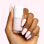 Hand holding Gelato nail polish bottle showing soft baby pink gel polish on long manicured nails.
