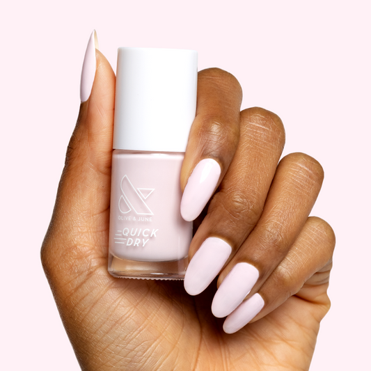 Hand holding Gelato nail polish bottle showing soft baby pink gel polish on long manicured nails.