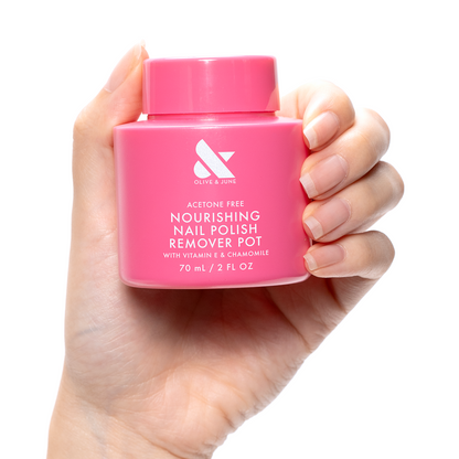 Hand holding a pink Nourishing Remover Pot with vitamin E and chamomile for gentle nail polish removal